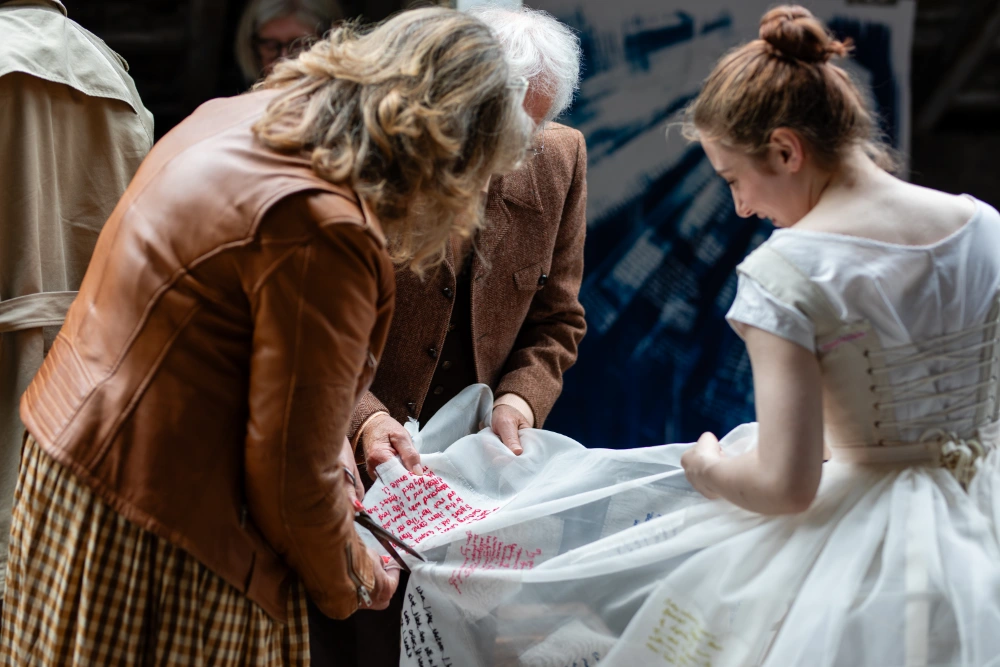 Viewing the embroidered writting on the dress, Hannah Lamb